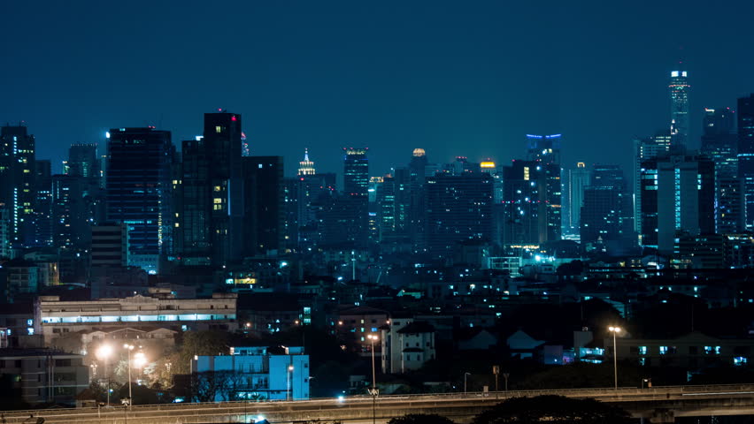 Buildings in city night and lights streak traffic, time lapse.