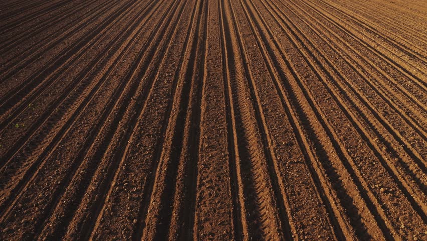 Plowed farmland soil from drone pov, aerial shot, high angle view