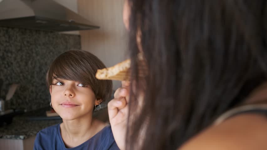 Non-binary child smiling while having breakfast with the family
