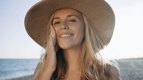 Video of beautiful smiling woman applying sunscreen on her face while looking at camera at the beach. - Powered by Shutterstock - Get 15% off with code: PIKWIZARD15