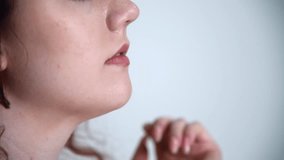 Close-up side view of beautiful caucasian woman touching her nose, lips and chin with her fingers. Female skin with acne. Soft focus. Real time handheld video. Beauty and skincare theme.