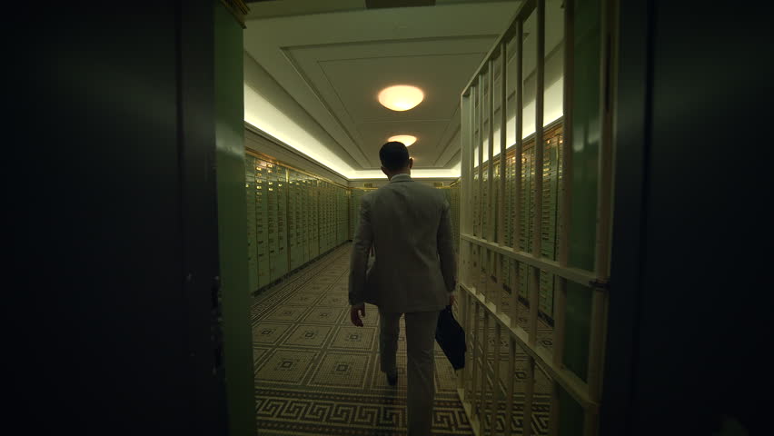 A man is strolling through a dimly lit hallway with rows of lockers