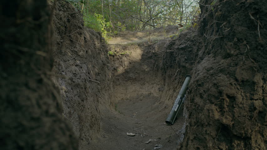 Two male soldiers or military men in camouflage uniform and helmets sneak up in trench and attack enemy positions shooting from rifles during battle in forest. War or military conflict. Armed forces.