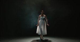 4K video footage beautiful woman ballerina in white tutu on black background, slow motion