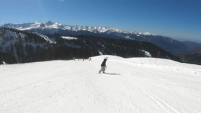 Woman riding snowboard in the mountains. Freeride snowboarder girl in sports equipment riding snow high in mountains in Ski resort. Winter snowboard touring recreation, extreme vacation concept.