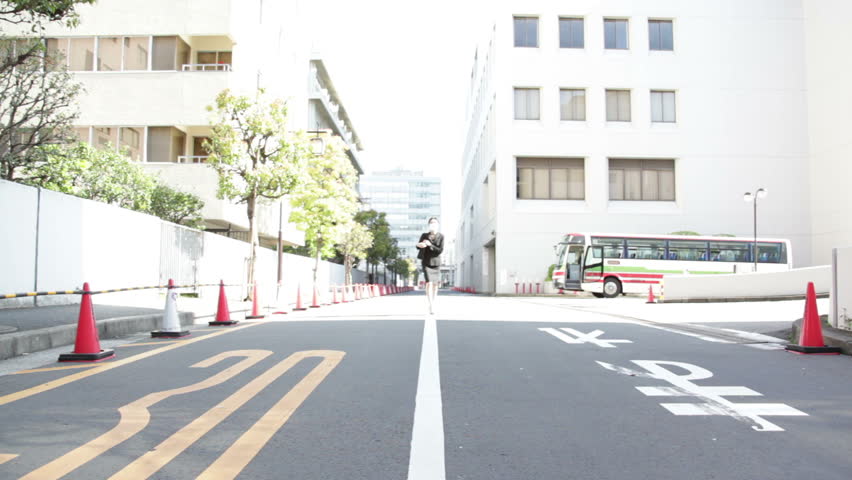 Japanese business woman in black suit walks in the office disctrict