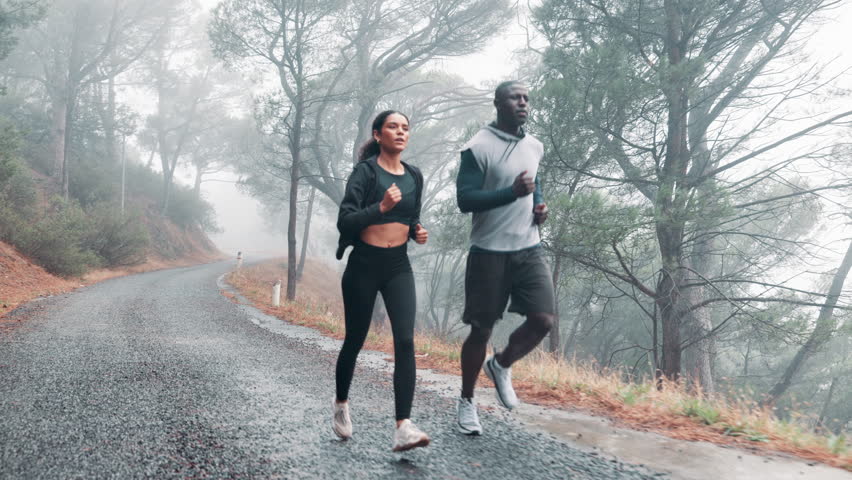 Healthy, running and couple with fitness, exercise and rain with wellness and training with endurance. Cardio, outdoor and wet road with man and woman with a hobby and runner with sports and progress