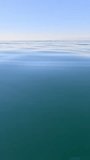 Vertical aerial view on sea water surface, camera flies over clear sea water. Sun glare. Abstract nautical summer ocean nature. Holiday, vacation and travel concept. Nobody. Weather and climate change