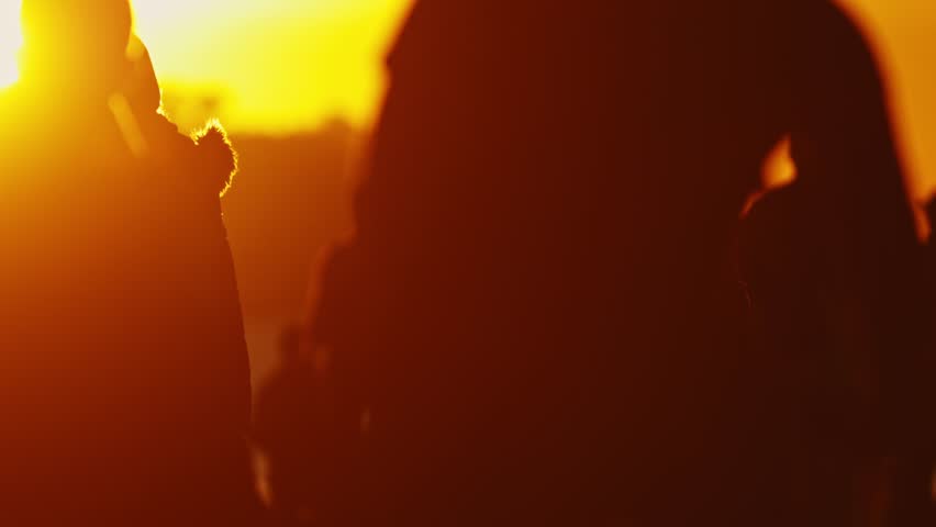 Silhouette of crowd people walking in front of bridge at sunset