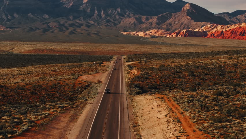 Cars on a highway in Nevada USA with Red Rock Canyon in the background, aerial view during sunset