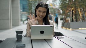 Beautiful white businesswoman meeting using digital tablet video conference outside office. Successful corporate staff, professional occupation person, sales manager, business coach posing.