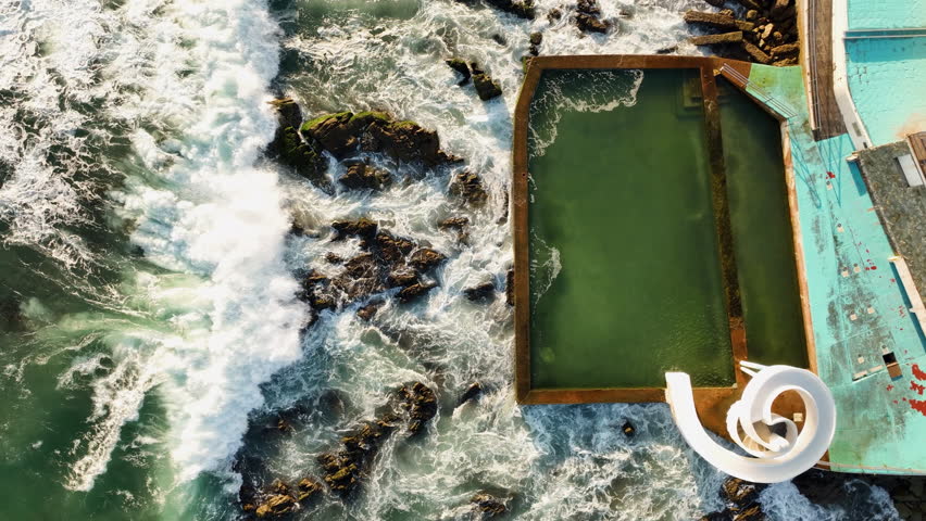 Top down drone shot of waves hitting a pool and a waterslide in Mazatlan, Mexico