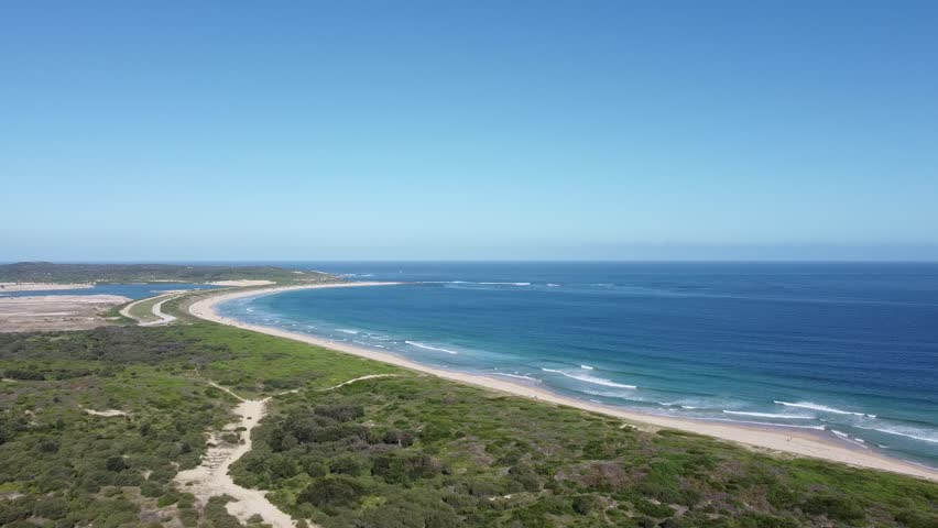 Slow moving panoramic aerial shot of the famous Cronulla beach and coastline on a clear cloudless day with lots of beach activity