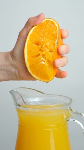 The process of squeezing orange juice from half a fresh orange, slow motion vertical shooting.