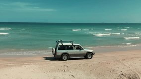 Aerial top view of the trash beach by the sea in Nha Trang at sunset,Cam Ranh, Vietnam. Top down view of a car with boards on the roof for surfing, car drives along the sand on the beach on the sea - Powered by Shutterstock - Get 15% off with code: PIKWIZARD15