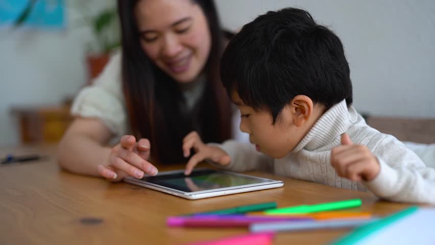 Asian mother and male child using digital tablet indoor - Daycare, technology and education concept 