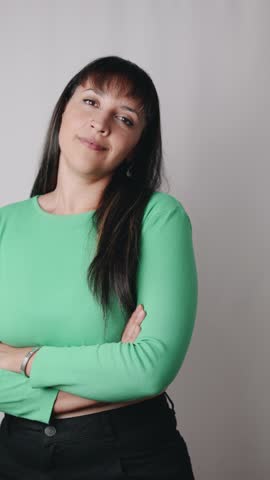 Latin American woman wearing casual green blouse is looking aside pointing with eyes to empty space for advertisement.	
