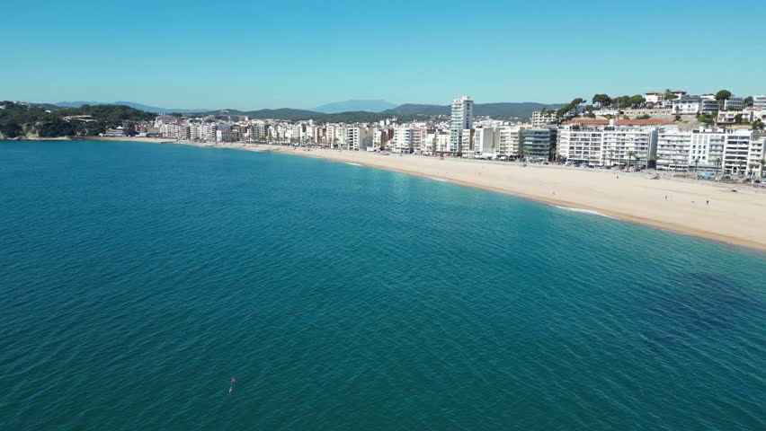 Panoramic aerial view of the city Lloret de Mar in Spain with its coastline, beach and houses on sunny day, 4K