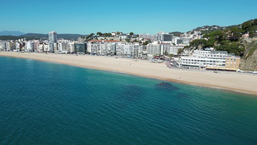 Panoramic aerial view of the city Lloret de Mar in Spain with its coastline, beach and houses on sunny day, 4K