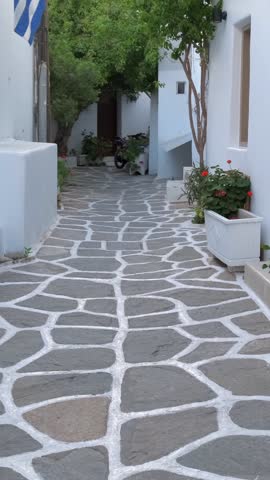 Walking with steadycam in picturesque narrow street with traditional whitewashed houses with blooming bougainvillea flowers of Naousa town in famous tourist attraction Paros island, Greece