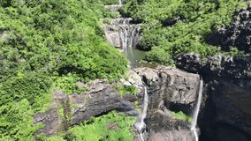 flying uphill the Tamarind Falls, aka Seven Cascades in the tropical island jungle of Mauritius with people swimming in the different ponds - aerial video footage 