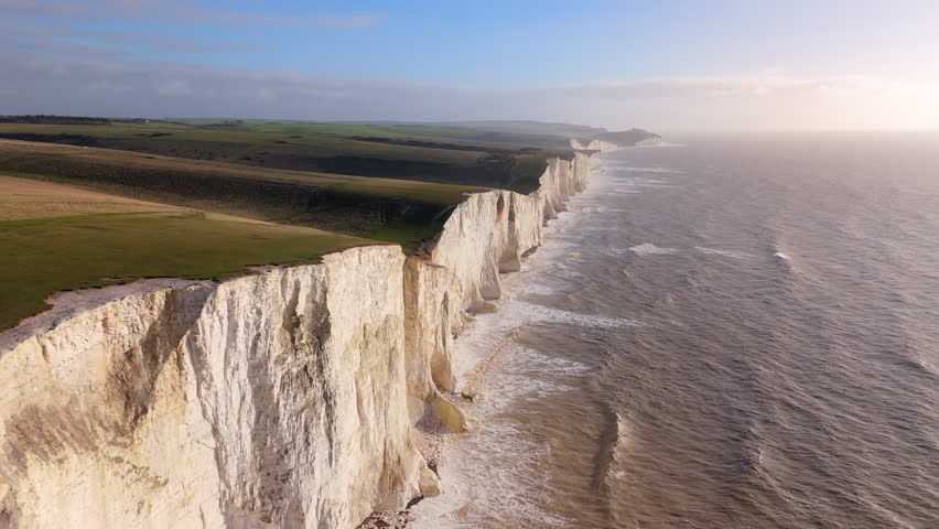 Towering white cliffs alongside the sea glow under the golden light of sunset, creating a breathtaking natural landscape symbolizing endurance and beauty. Seven Sisters, Brighton, United Kingdom 