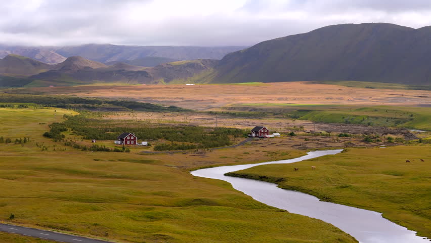 Breathtaking aerial view unfolds across Iceland vast plateaus, with sweeping views of barren lands leading up to distant snow-capped mountains, river epitomizing the stark beauty of Iceland. 