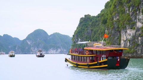 Several boats float between rocks. A bay in Vietnam. Vietnam. A travel in Vietnam. Tourists swim by the boat in a bay of Vietnam. Traditional Vietnamese tourist boats