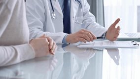 Doctor is consulting patient in modern clinic. Healthcare professional discusses medical information with a woman, gesturing above the glass desk. Medicine - Powered by Shutterstock - Get 15% off with code: PIKWIZARD15