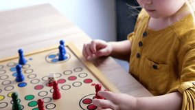 close-up of hands of small child manipulate with wooden figurines of family board game, smart kid, 2-year-old girl is learning to count, Cross and circle game Parcheesi, foreground focus - Powered by Shutterstock - Get 15% off with code: PIKWIZARD15