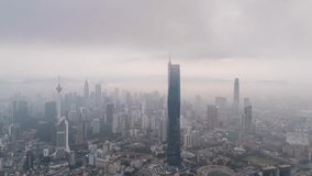 Aerial view time lapse 4k video of Kuala Lumpur city center view at sunrise dawn overlooking the city skyline in Federal Territory, Malaysia during low clouds sunrise. Tilt down