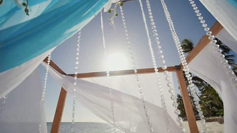 A wedding arch decorated with flowers and large wind-developing fabrics on a tropical beach. Shooting in motion. Philippines. Bohol.