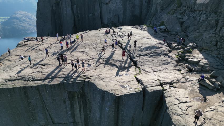 Witness awe-inspiring views of Preikestolen, Norway, as people marvel at the stunning Norwegian fjords from this iconic cliff edge.