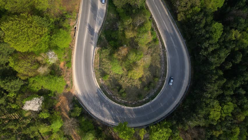 Mountain road seen from a drone. High angle fotoage of vehicles traversing a picturesque mountain curve of Shipka pass in Bulgaria. A busy European forrest road seen from above. Cars trucks driving