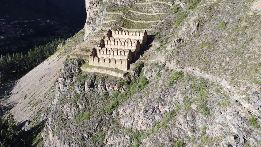 Historic town site of Ollantaytambo cut out of hillside in Peru, aerial ascend