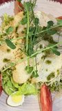 Stock food video of chicken Caesar salad with croutons, parmesan cheese and microgreens served on white plate in Mediterranean restaurant and filmed Caesar salad with microgreens