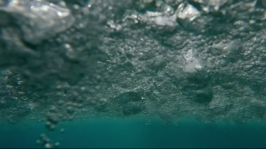 Underwater view of seeing water surface during thunderstorm in ocean, raindrops penetrate below water surface, Slow motion
