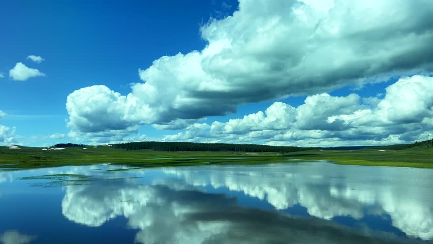 The scenic view of lake with reflecting clouds and sky while driving of the beautiful Yellowstone National Park in USA on a sunny day.