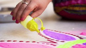Woman using a bottle of pour a mound of color onto the ground to make a colorful rangoli a traditional art made on floors during festivals of diwali, dussera, onam in hindu culture - Powered by Shutterstock - Get 15% off with code: PIKWIZARD15