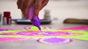 Slow motion shot woman filling purple color from a bottle into a rangoli a traditional art made on floors during festivals of diwali, dussera, onam in hindu culture - Powered by Shutterstock - Get 15% off with code: PIKWIZARD15