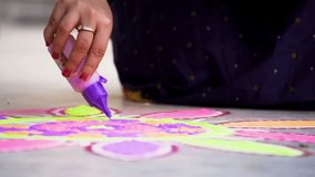 Indian woman using a bottle of purple color powder to fill in a rangoli a traditional art made on floors during festivals of diwali, dussera, onam in hindu culture - Powered by Shutterstock - Get 15% off with code: PIKWIZARD15