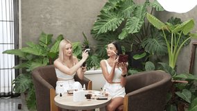 Two beautiful content creator making natural beauty and cosmetic tutorial on green plant leave garden video. Beauty blogger showing how to apply beauty care to social medial audience. Blithe