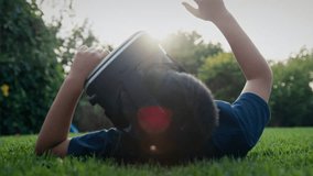 Boy lying on his back on grass and looking into a virtual reality headset - Powered by Shutterstock - Get 15% off with code: PIKWIZARD15