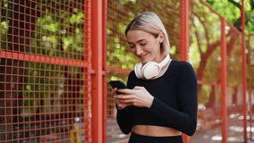 Happy young woman texting on her phone after fitness training outdoors. Sport and healthy lifestyle concept - Powered by Shutterstock - Get 15% off with code: PIKWIZARD15