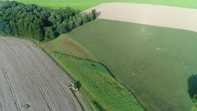 Flying over a yellow Combine harvester threshing the wheat– aerial video taken from above with a drone