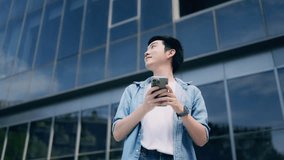 Handsome Asian student using smartphone. A young man standing outdoor happy smiling with holding mobile phone - Powered by Shutterstock - Get 15% off with code: PIKWIZARD15