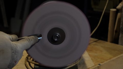 Sharpening a chisel on grinding machine with fly sparks