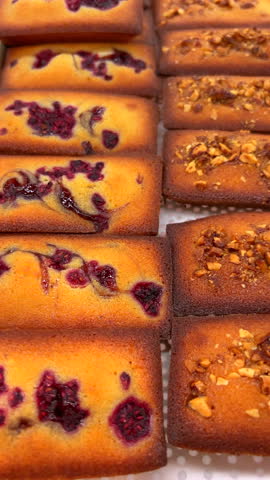 Assorted freshly baked fruit and nut pound cakes displayed at local farmers market. Artisanal homemade desserts perfect for gatherings. Culinary arts and small business.