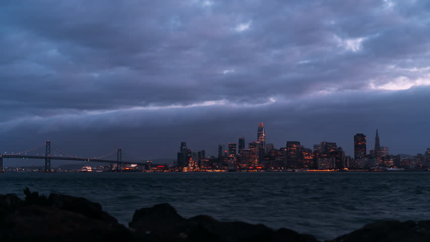 Timelapse of Oakland Bay Bridge and San Francisco city with clouds in the dark evening sky, California, USA