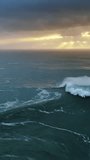 Aerial view on big waves of Atlantic ocean and dramatic sunset sky. Vertical video